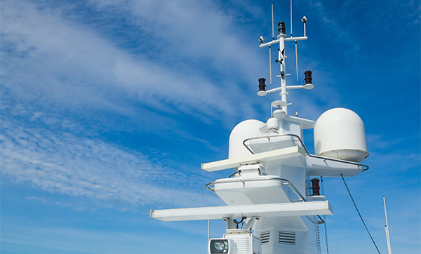 Marine electronics equipment on a yacht mast against a clear blue sky.