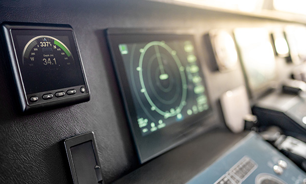 Navigation equipment displaying compass and radar readings on a boat dashboard.