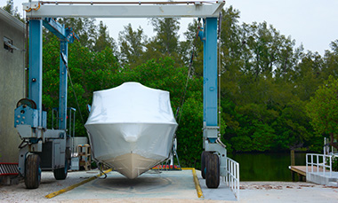 Boat on a lift for maintenance surrounded by trees at a marina.